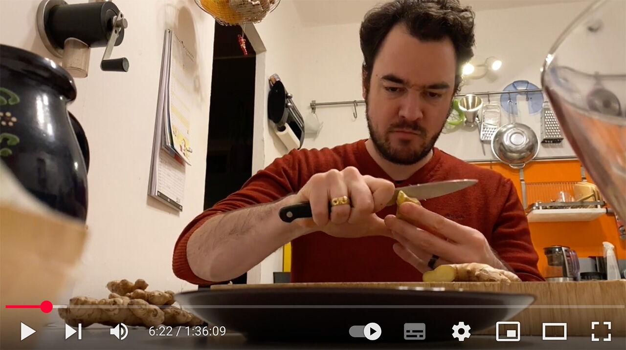 Matthias Warkus in einem roten Pullover schält konzentriert Ingwer in seiner gemütlichen Küche.