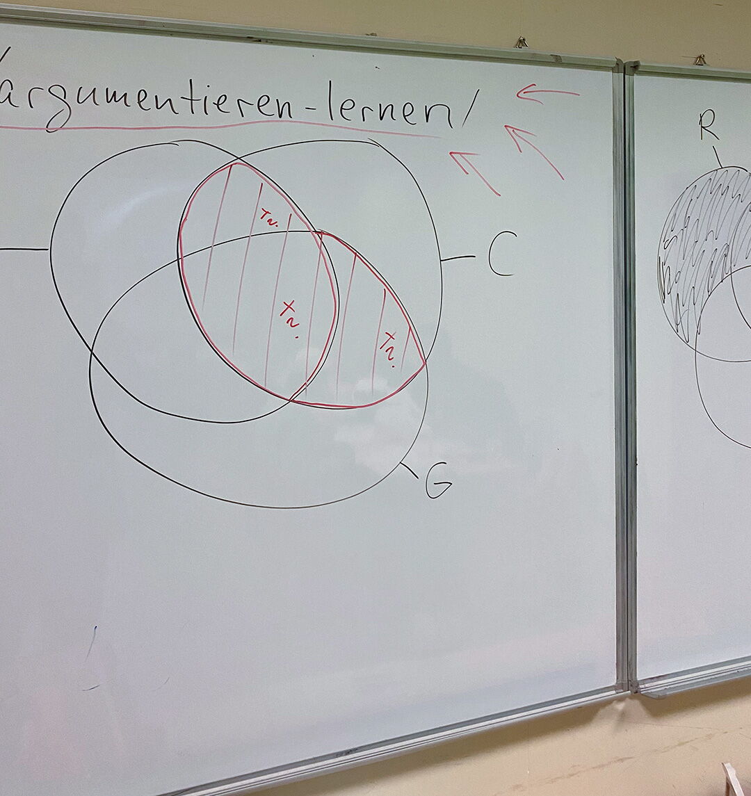 Ein Whiteboard zeigt eine Skizze zum Thema "Argumentieren lernen" im Wochenend-Crashkurs Philosophie